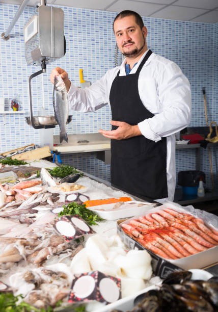 istock Seller in black apron showing fish 980803084