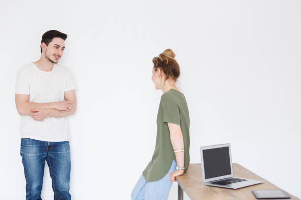istock Business people In office. Two talented designers working, sharing Idea. handsome smiling young man and woman sitting at workplace with notebook, discussing on project together. White wall background 980809060