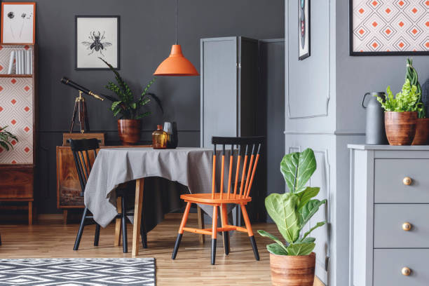 istock Old fashioned dining room interior with a table, chairs, orange lamp and plants 980809396