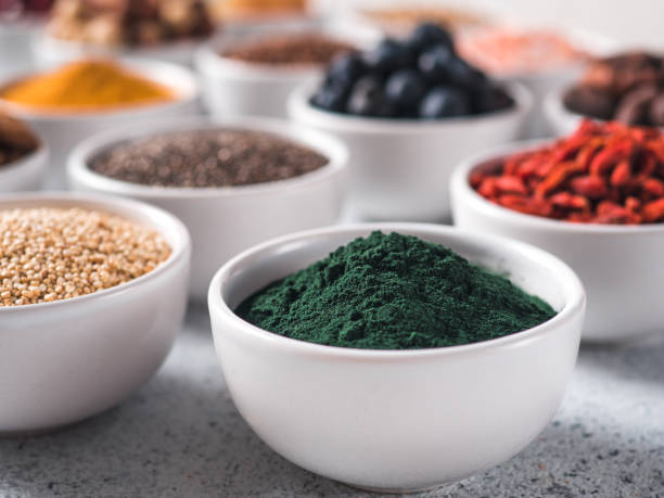 Spirulina in small white bowl and other superfoods stock photo