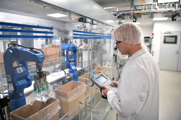 conveyor belt arbeiter betreibt einen roboter, der insulin-taschen - moderne fabrik für die herstellung von medikamenten im gesundheitswesen transportiert - quality control safety factory industry stock-fotos und bilder