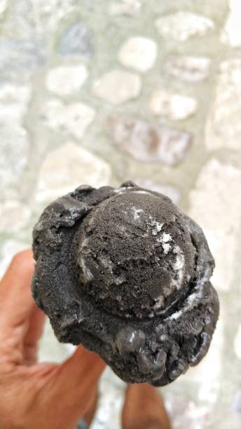 istock Hand holding black ice cream in a waffle cone 980813610