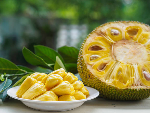 buah jack segar dalam hidangan putih, setengah dari buah jack dan daun buah jack di atas meja kayu. - nangka potret stok, foto, & gambar bebas royalti