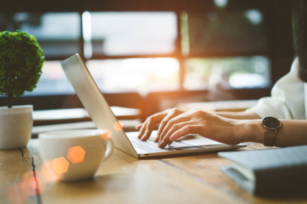 mani ravvicinate di donna freelancer che lavora utilizzando computer portatile digitale e bevono colazione al caffè sul tavolo del posto di lavoro al bar al mattino. - typing foto e immagini stock