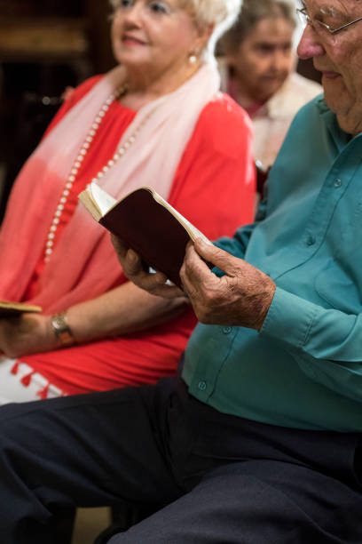 istock Senior man pages through hymn book in chapel 980855544