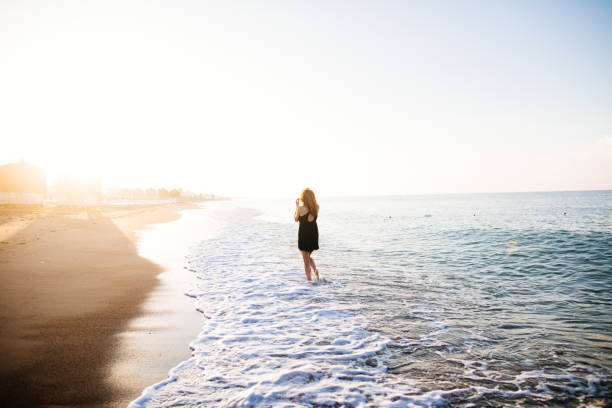 istock Woman walking on beach at sunrise 980857002