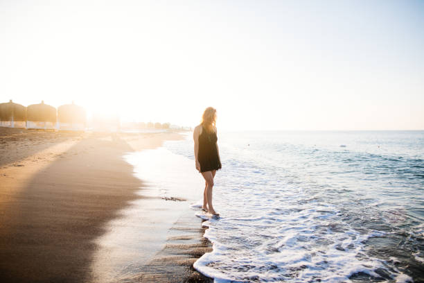 istock Woman walking on beach at sunrise 980857008