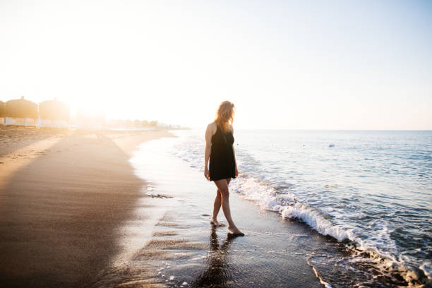 istock Woman walking on beach at sunrise 980857612