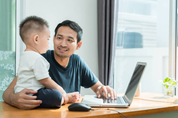 istock Asian father and little son typing something on laptop computer on workplace at office home happiness laughing together, happy family concept. 980861870