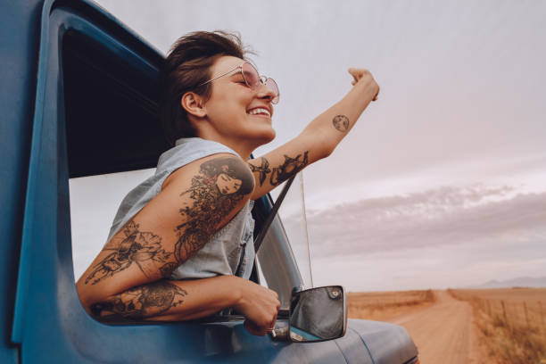 attraktive junge frau auf einem roadtrip genießen - tattoo stock-fotos und bilder