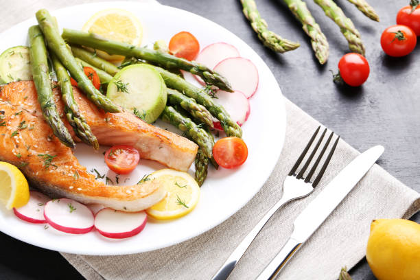 istock Steak of salmon with asparagus, vegetables, fork and knife 980871028