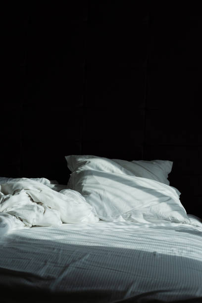 istock Messy bedding sheets and pillows, sunshine through window in the morning 980879774