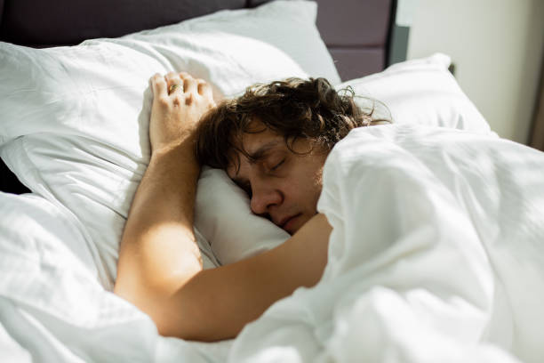 istock Blond men is sleeping alone in bed with white bedclothes (selective focus) 980879780