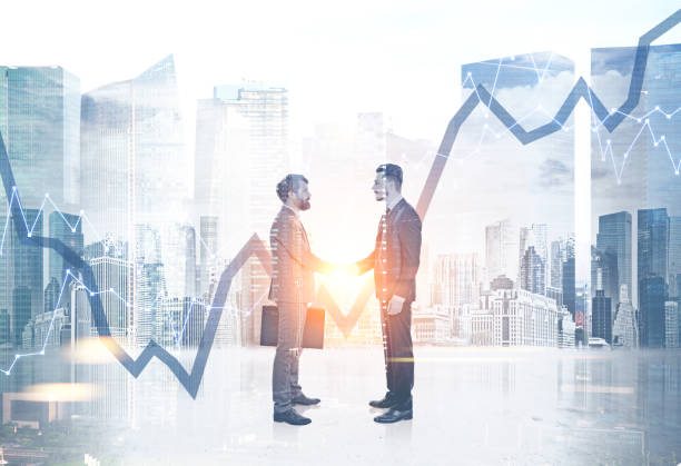 istock Business people shaking hands in a city, graphs 980880032
