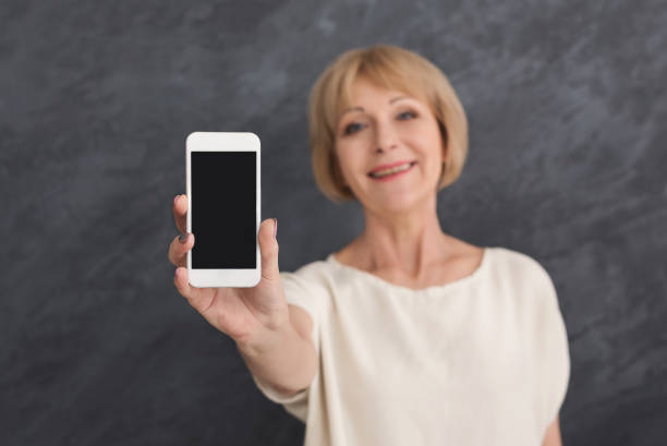 istock Smiling mature woman holding smartphone with blank screen 980880202