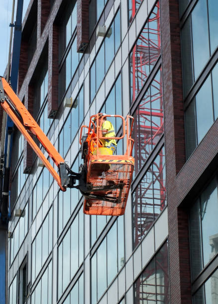pracownik budowlany na pomarańczowej platformie na dużym nowoczesnym placu budowy - tabard zdjęcia i obrazy z banku zdjęć