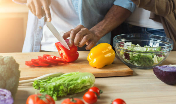 Black man preparing vegetable salad Black man cutting vegetables for healthy vegetarian salad in kitchen, closeup chopping food photos stock pictures, royalty-free photos & images
