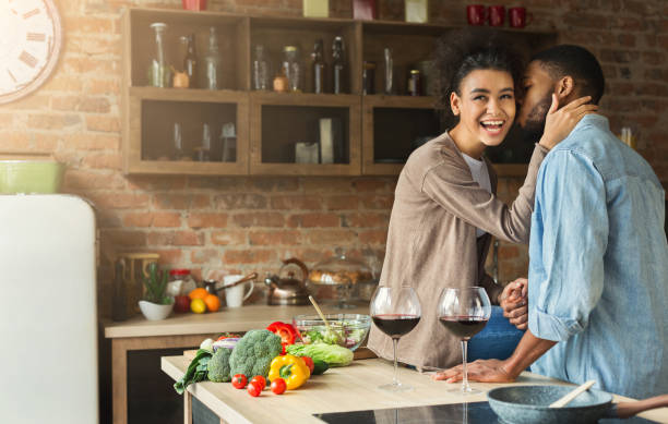 istock Loving african-american couple drinking wine in kitchen. 980887690