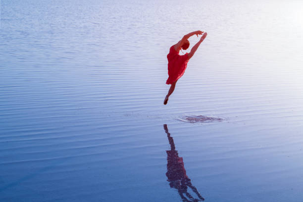 istock Ballerina dancing on the water with classical dress 980888926
