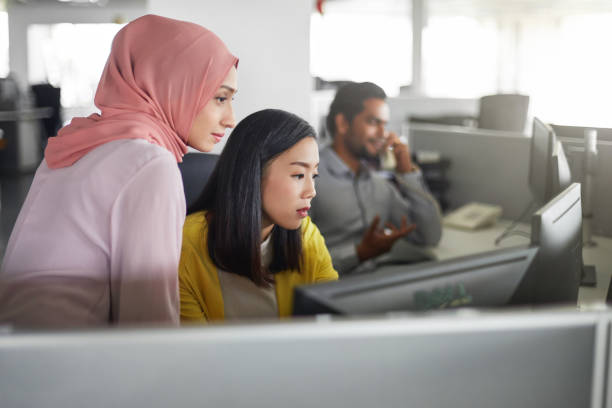 kvinnliga kollegor som arbetar på databord - business malaysia bildbanksfoton och bilder