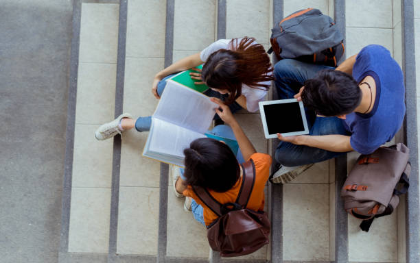 istock Students university asian together reading book study smiling with tablet at high school campus,college in summer sitting ladder top view. 980908146