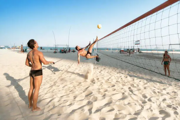 brazilian man kicking soccerball over volleyball net at beach in Rio de Janeiro