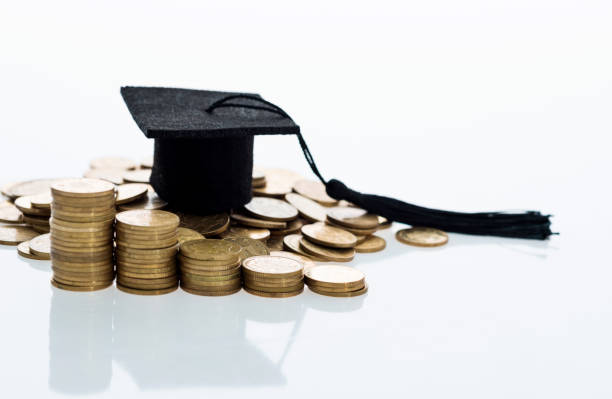 istock Graduation hat and heap of coins 980908300