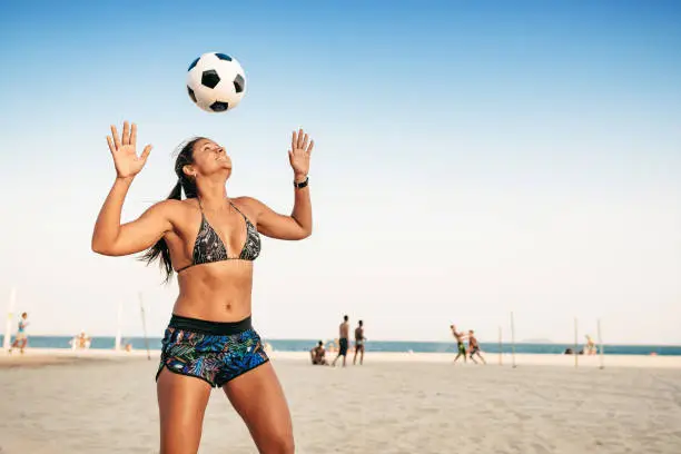 Photo of brazilian woman juggling ball on head at beach in Rio de Janeiro