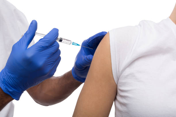 istock Black male hand in blue gloves holding a plastic syringe 980931786