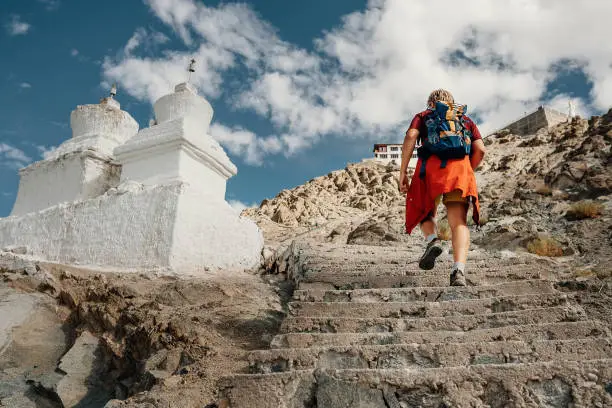 Tourist man climbs up stairs to tibetan holy place in Himalaya mountain
