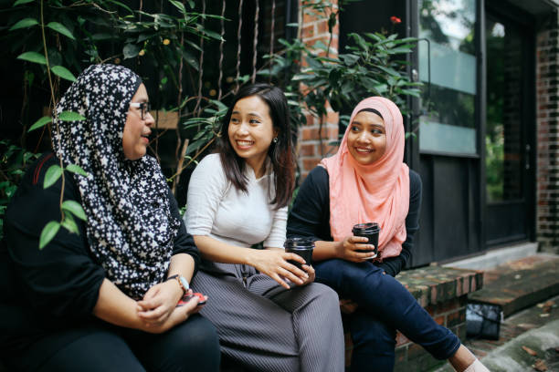 istock Female friends sitting outdoors in Kuala Lumpur, having a quick coffee, talking 980936290