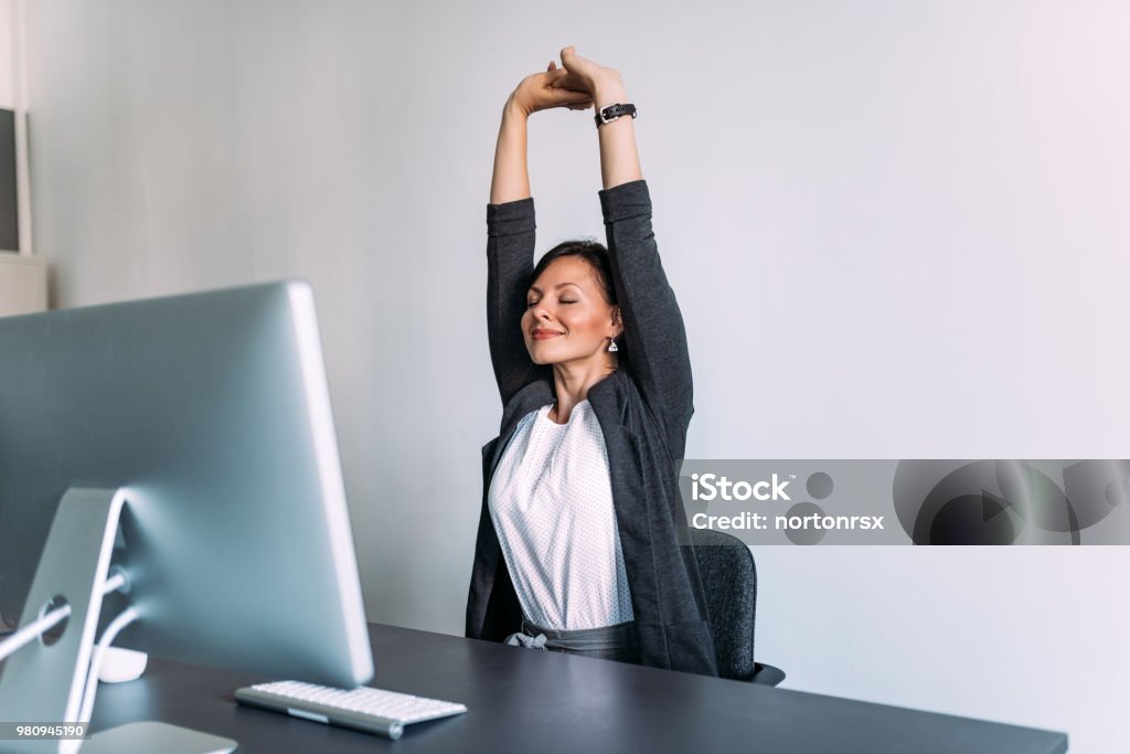Break at work. Female office worker stretching hands. Stretching Stock Photo
