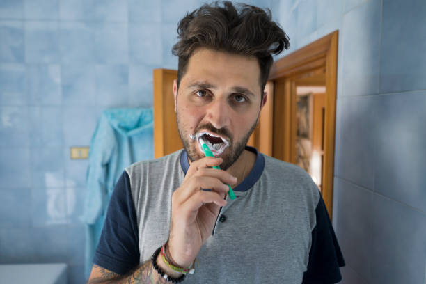 istock Young man in his pajamas brush his teeth 980953018