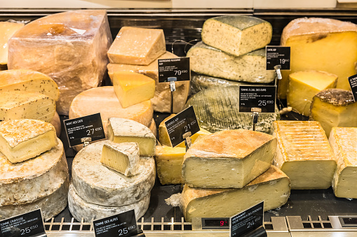 A large selection of different french and italian cheeses on  display in a French supermarket. Paris, France