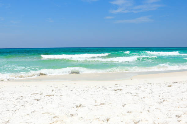 Sunny Summer day at the beach in Destin, Florida Waves hitting the sugar white beaches in Florida on a windy day. Vivid sky colors and emerald colored Gulf of Mexico waters. gulf of mexico photos stock pictures, royalty-free photos & images