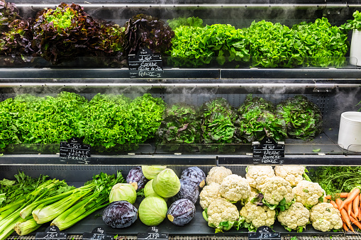 Assorted different kinds of fresh organic green vegetables on display in a French supermarket.  Background with cauliflower; cabbage; lettuce. Healthy vegetarian food concept. Paris, France