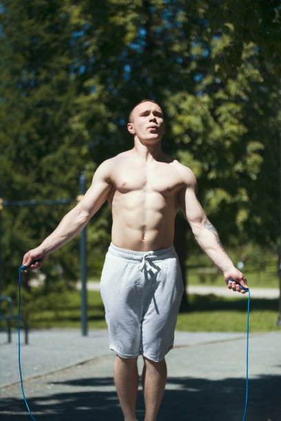 istock Athletic muscular man jumping with a rope, workout outdoors at sunny day 980959680