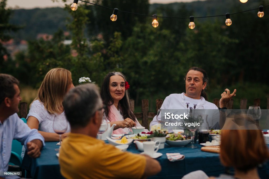 Al Fresco Dining Group of friends sitting, talking and enjoying al fresco dining. 40-49 Years Stock Photo