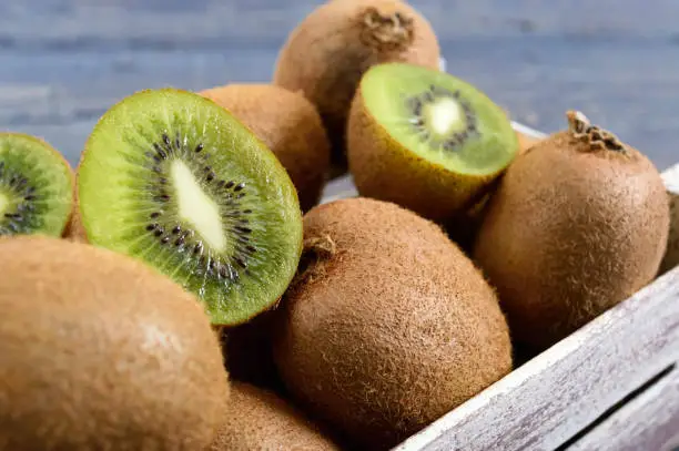 Photo of Fresh ripe kiwi fruit in a wooden box on the table. Tropical Fruit. Healthy food. Close up