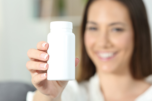 Close up of a happy woman hand showing a blank medicine bottle of pills