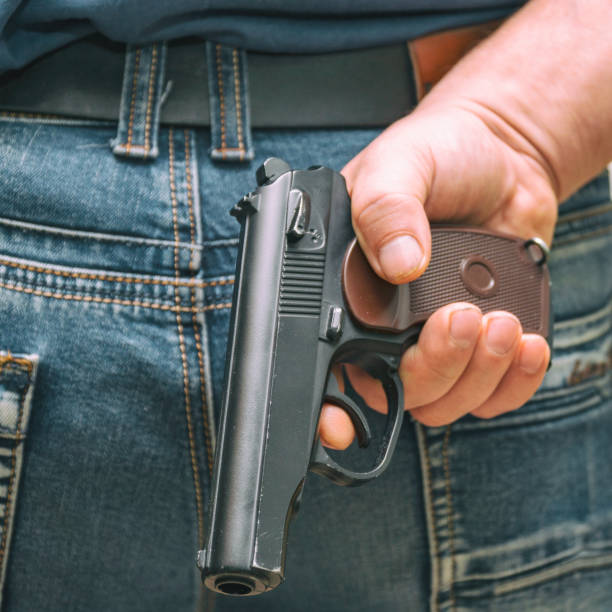 istock Man in jeans holding a gun behind his back 980979260