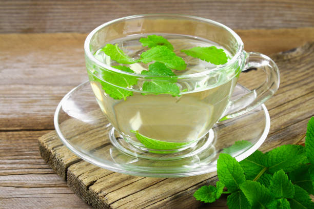 istock Fresh organic mint tea in glass on wooden table. 980986408