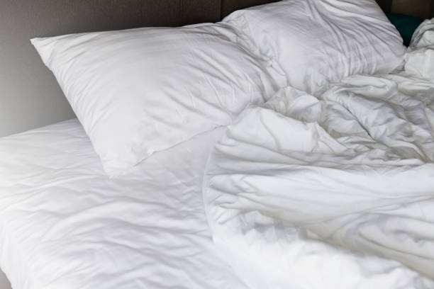 istock unmade rumpled bed with white messy pillows  in bedroom interior morning light 980987144