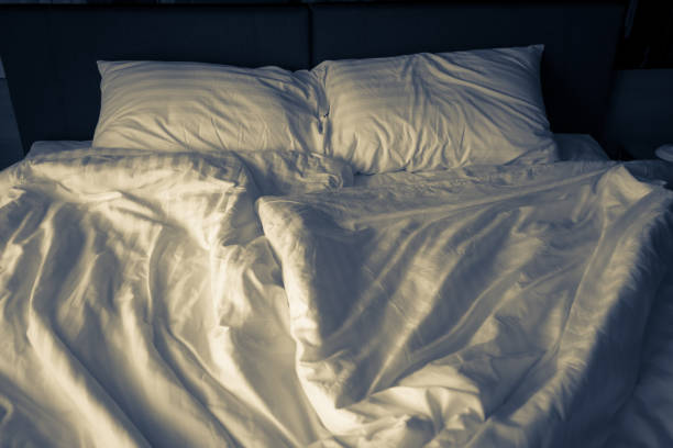 istock unmade rumpled bed with white messy pillows  in bedroom interior morning light 980987152