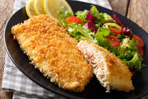 istock Fried fish fillet in breading and fresh vegetable salad close-up. horizontal 980989410