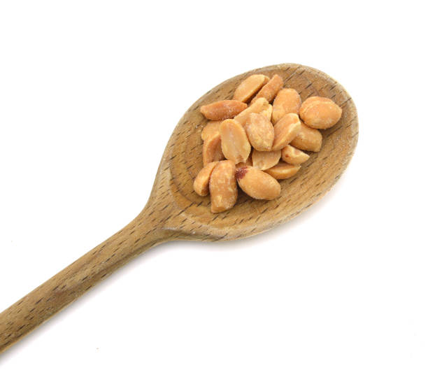istock Heaping pile of peanuts on wood spoon isolated on white 980992806