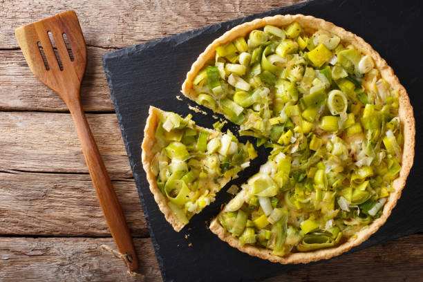 Sliced tart with leek and cheese close-up. Horizontal top view Sliced tart with leek and cheese close-up on the table. Horizontal view from above savoury pie stock pictures, royalty-free photos & images