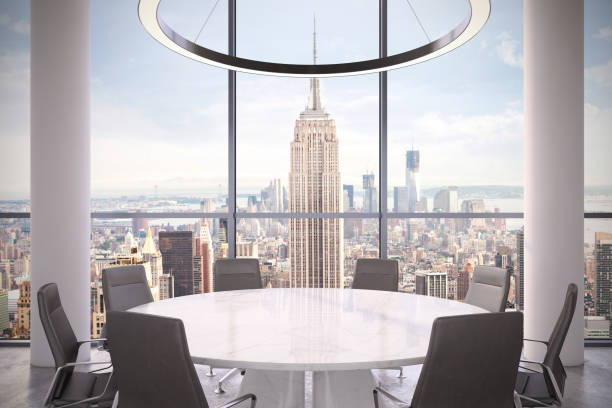 istock Office interior with large round desk and chairs with view at Empire state building 981003112