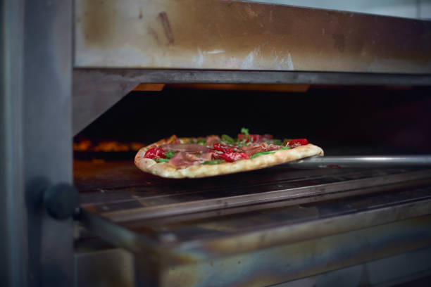 istock Cook putting Italian pizza to bake in oven 981003198