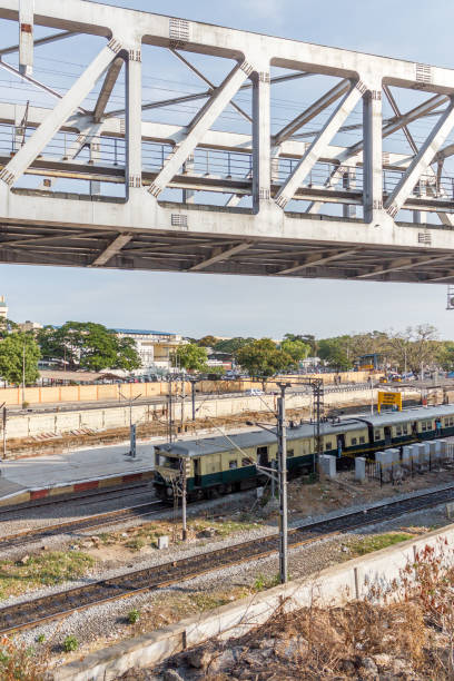 istock guindy (as written in tamil language) railway station seen with tracks and traffic signal post with electrical posts that supply power for running the trains 981003534